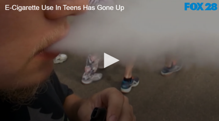 close shot of teen blowing out vape smoke from mouth