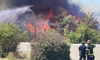 Fire crews battle Clarkston house fire spreading to field